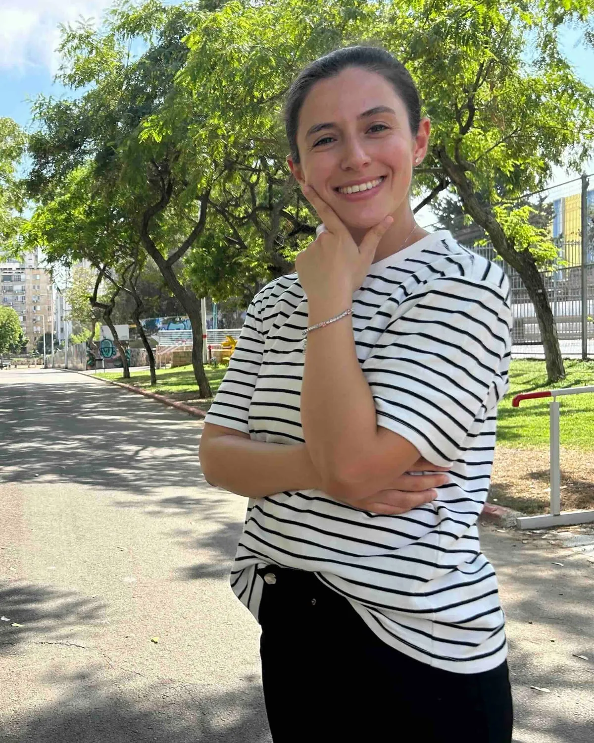 עדן בן-אור וגנר עומדת בשביל מוצל, בחיוך רגוע